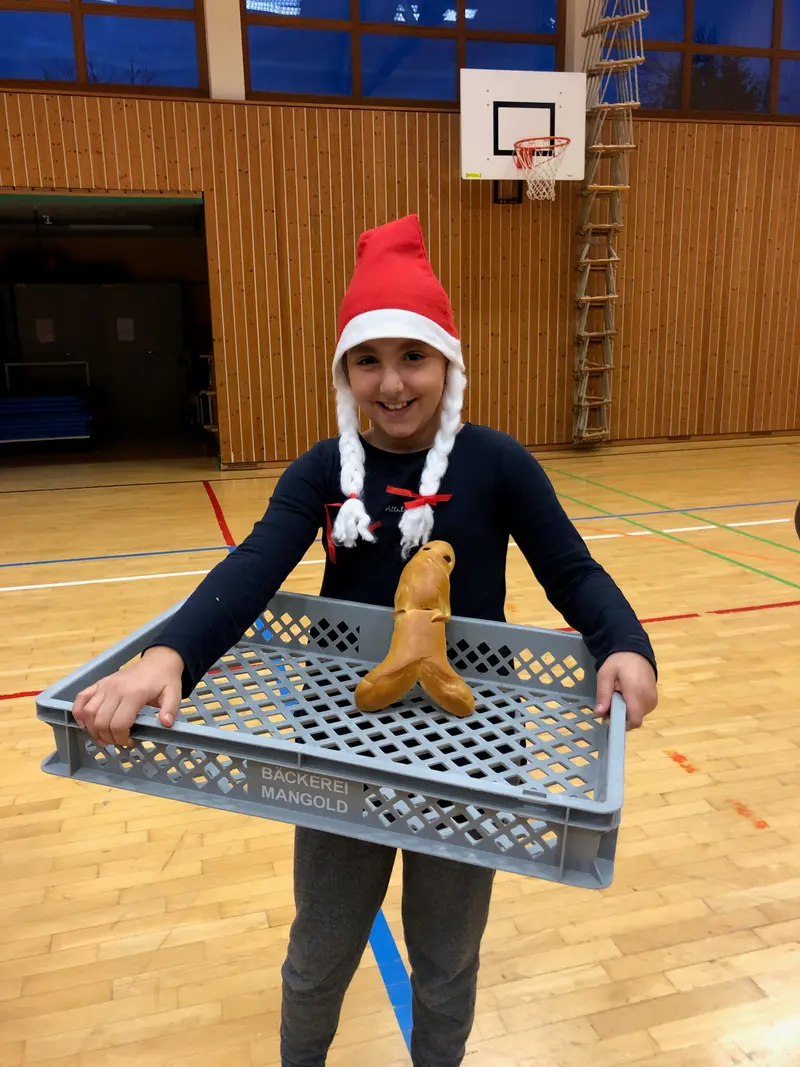 Kind mit Nikolausmütze hält einen Korb mit Gebäck