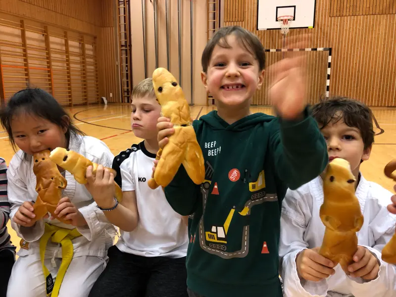 Drei Kinder halten lachend Gebäckfiguren in die Kamera