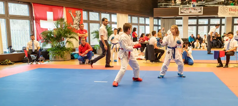 Kampfrichter beobachtet Kumite zweier Jugendlicher auf der Matte
