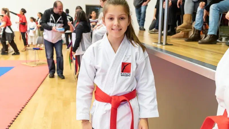 Kind im Karategi mit rotem Gürtel steht in der Halle