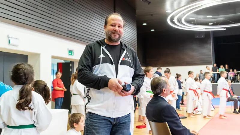 Person steht lächelnd in der Halle, im Hintergrund Kinder