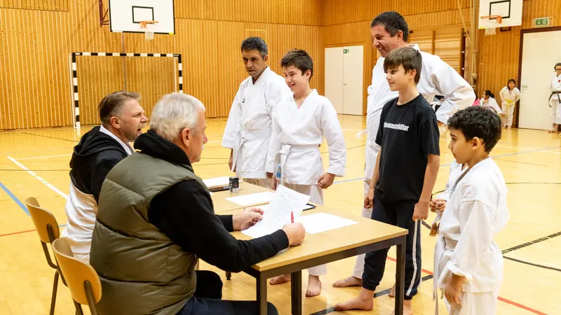Prüfer sitzen am Tisch, Jugendliche stehen davor