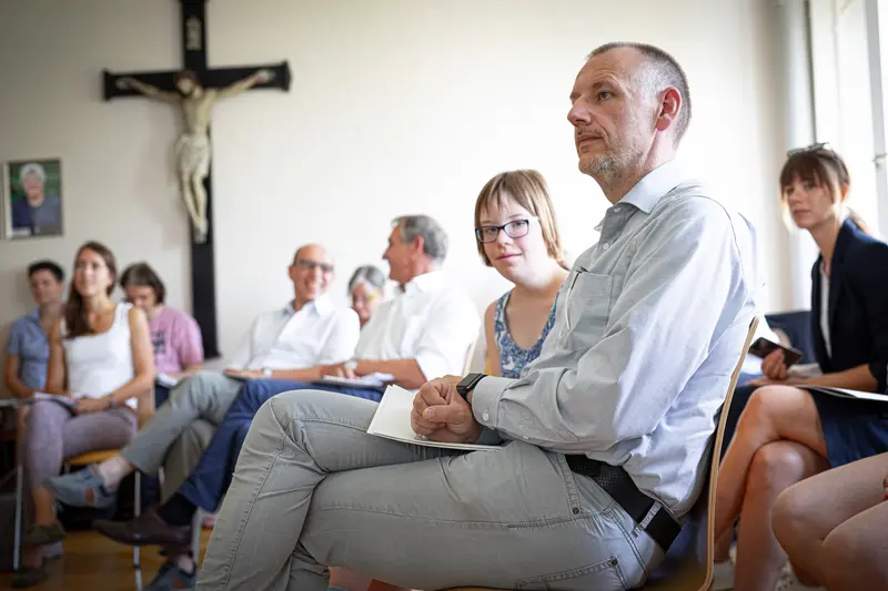 Person mit Brille sitzt aufmerksam im Publikum.