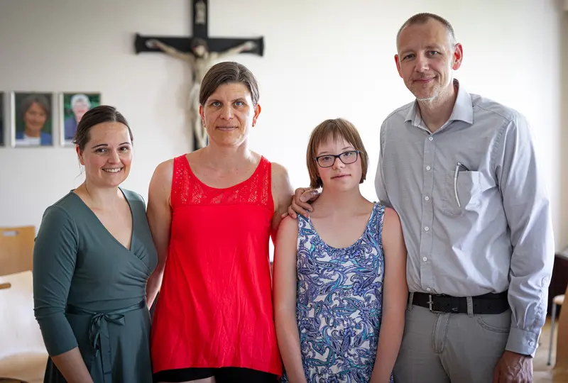 Vier Personen stehen lächelnd zusammen für ein Gruppenfoto.
