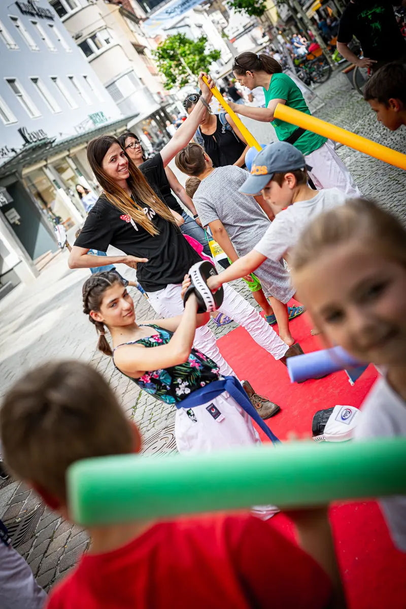 Kind übt Schlagtechnik gegen aufblasbares Trainingsgerät auf rotem Teppich