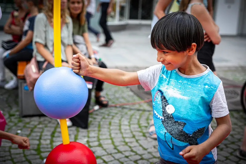 Kind schlägt gegen blauen Reflexball an Stange