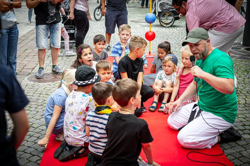 Trainer sitzt mit Kindergruppe im Kreis auf der Straße