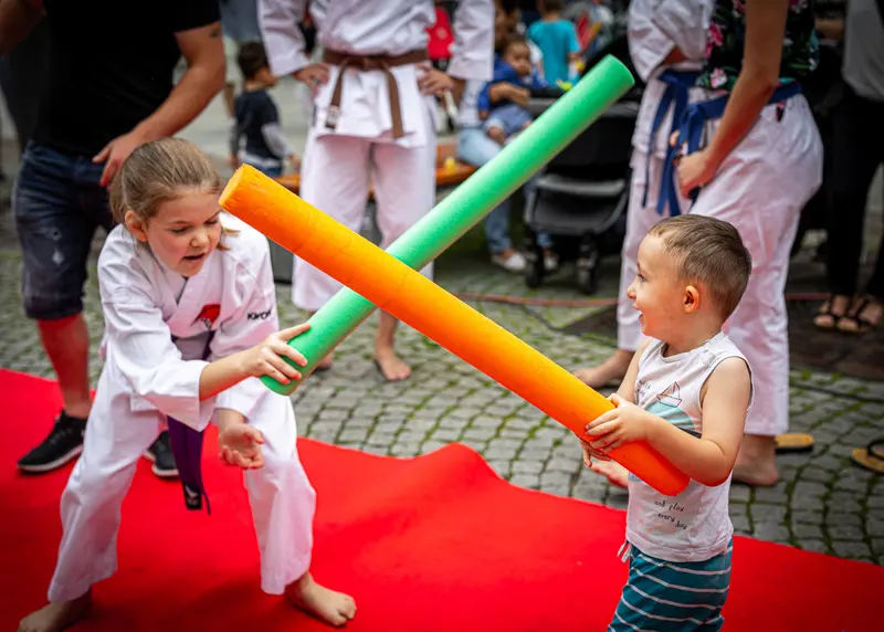 Zwei Kinder im Karategi kreuzen Schaumstoffstangen wie beim Fechten