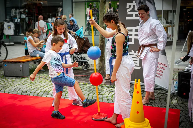 Kind übt Tritt gegen Reflexball unter Anleitung