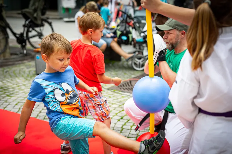 Zwei Kinder üben Tritttechnik gegen blauen Reflexball