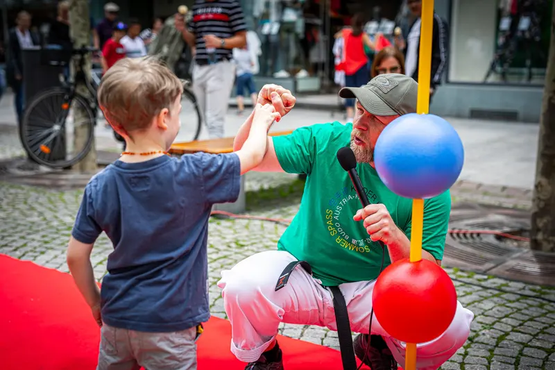 Kind und Trainer klatschen sich vor Reflexball-Stange ab