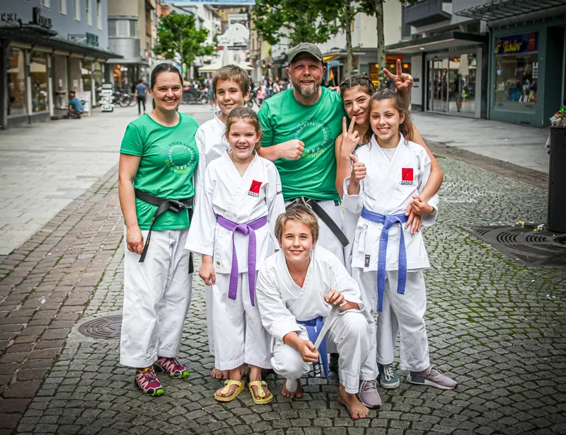 Gruppenfoto von Trainer und Kindern in Karategi mit violetten Gürteln