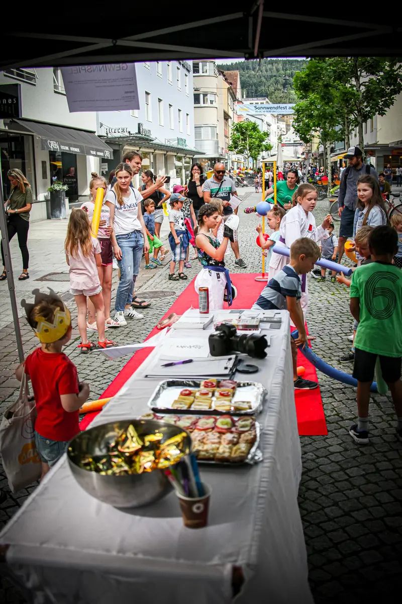 Kinder und Erwachsene versammeln sich bei einem Stand auf der Straße