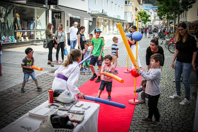 Kinder spielen mit Luftballons auf rotem Teppich in der Fußgängerzone