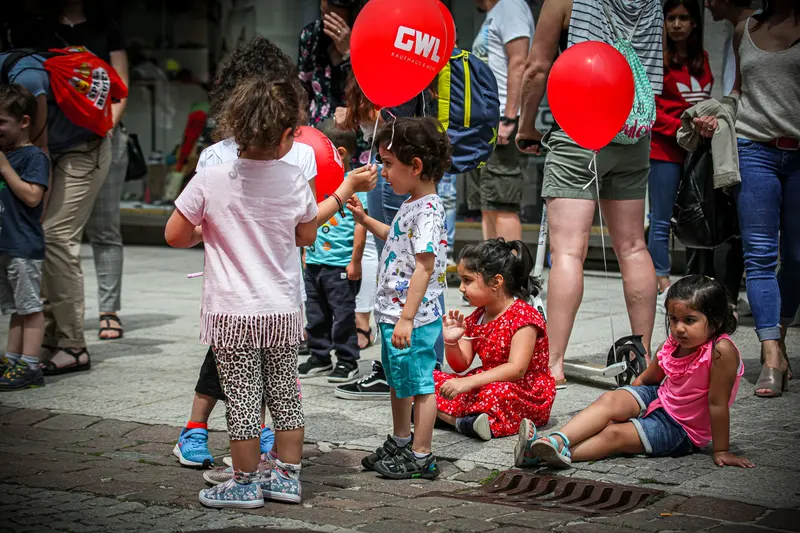 Kinder stehen bei bunten Luftballons auf Ständern in der Fußgängerzone