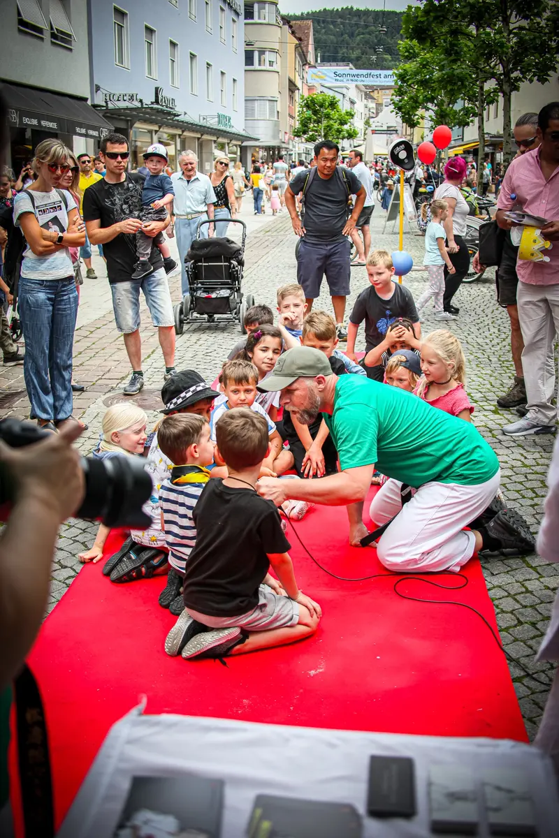 Person filmt eine Gruppe Kinder, die sich um einen Betreuer versammeln