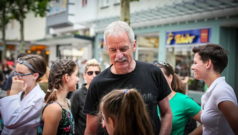 Person steht umgeben von mehreren Kindern auf der Straße