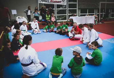 Gruppe von Kindern sitzt im Kreis, Trainer erklärt eine Übung