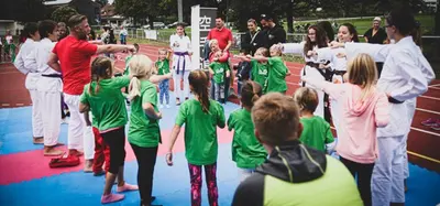 Trainer übt mit Kindern eine Abwehrtechnik im Kreis