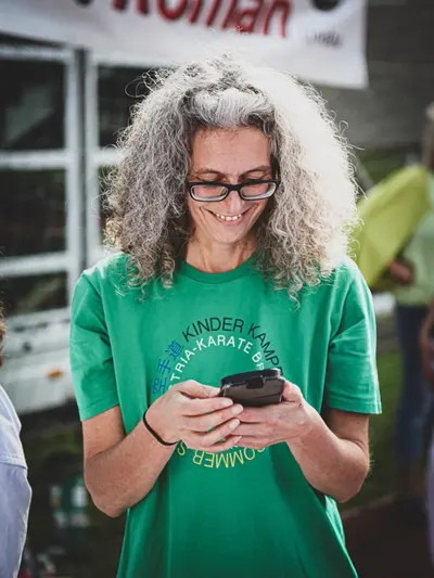 Person schaut lächelnd auf ihr Mobiltelefon