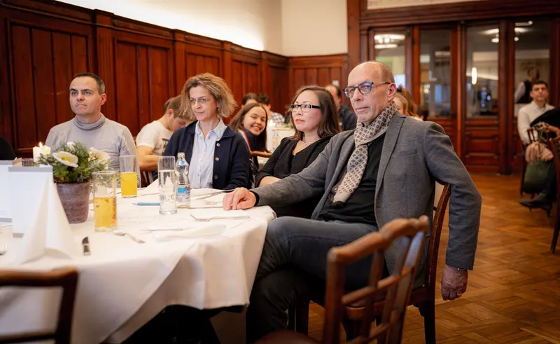 Gruppe sitzt an einem gedeckten Tisch im Gastraum
