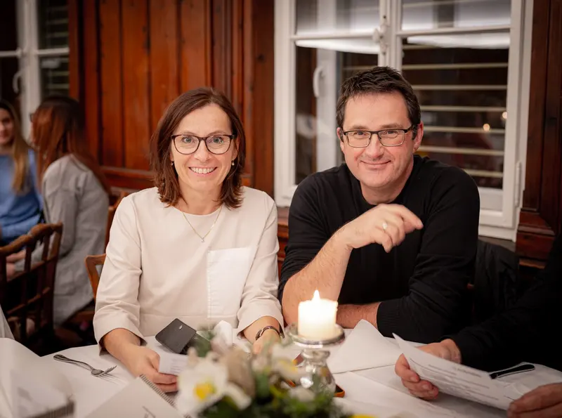 Zwei Personen sitzen lächelnd am Tisch mit Kerze