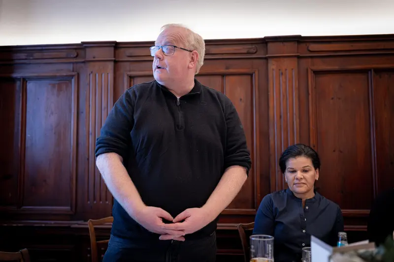 Person hält stehend eine Rede am Tisch im Gastraum