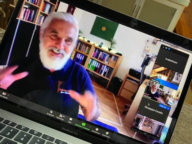 Person gestikuliert vor Laptop mit Videokonferenz