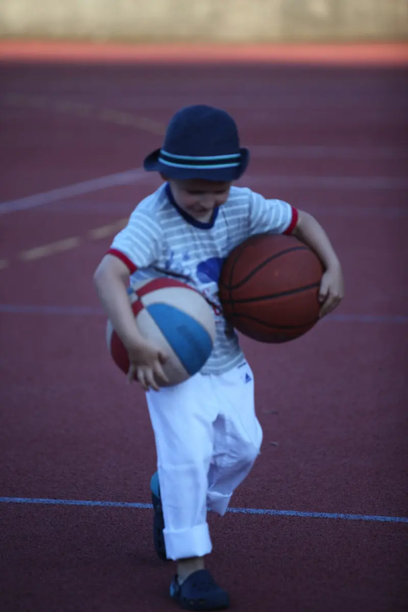 Kind spielt mit Basketball auf einem Sportplatz