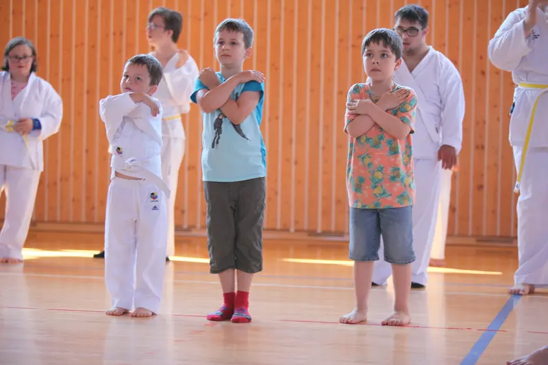 Drei Kinder stehen mit verschränkten Armen in Sporthalle