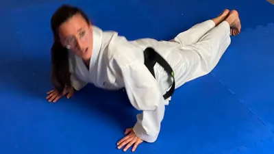 Person im Karategi bei einer Bodenübung auf Trainingsmatte