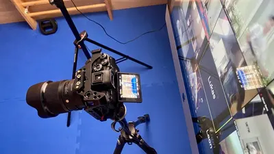 Kamera auf Stativ filmt vor blauem Hintergrund