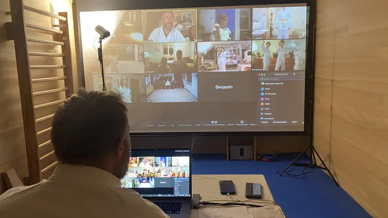Person sitzt vor Bildschirm mit Ansicht der Videokonferenz