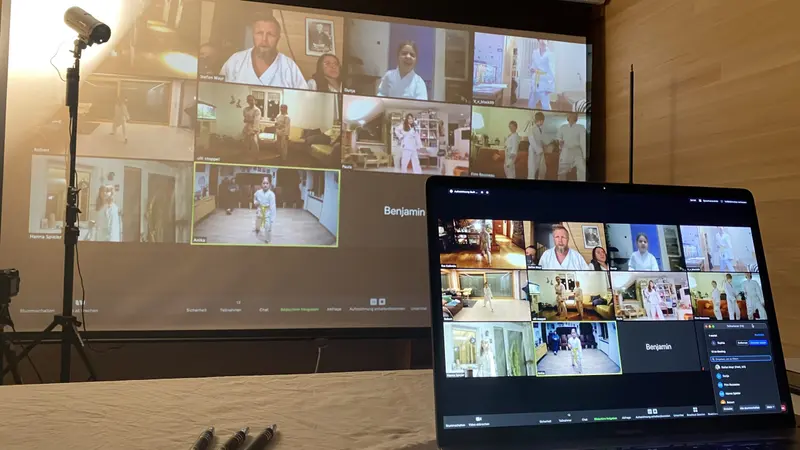 Laptop und Bildschirm zeigen Teilnehmende der Videokonferenz
