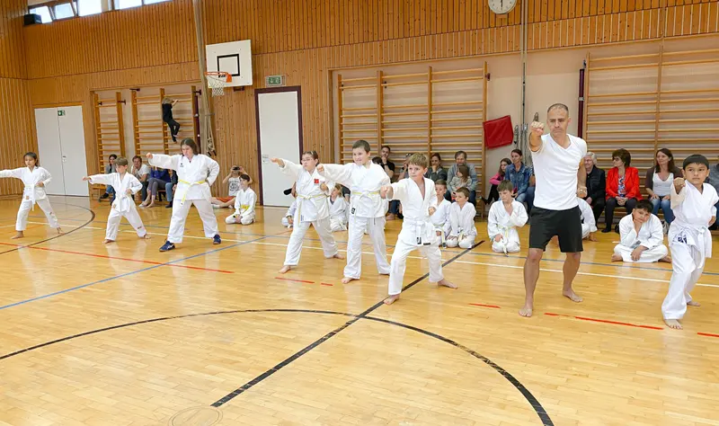 Trainer und Kinder üben gemeinsam eine Technik