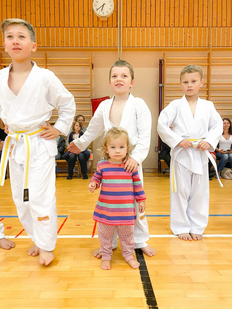 Zwei Kinder und ein Kleinkind stehen nebeneinander