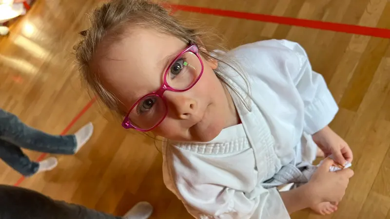 Kind mit Brille blickt neugierig in Kamera