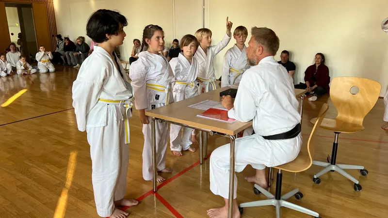 Kinder sitzen vor dem Prüfer am Tisch