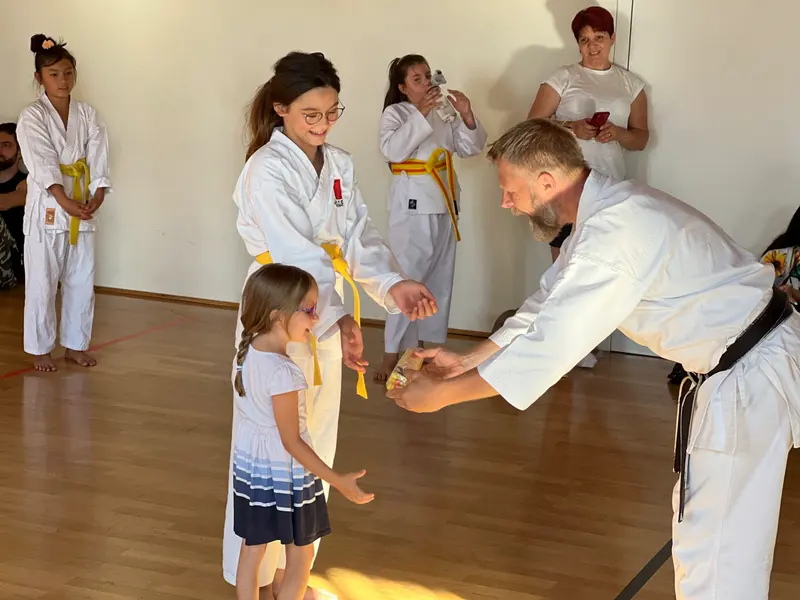 Prüfer beugt sich zu kleinem Kind für Handschlag