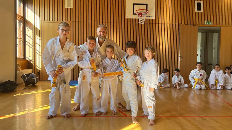 Gruppe Kinder mit Gürteln, Erwachsene im Hintergrund
