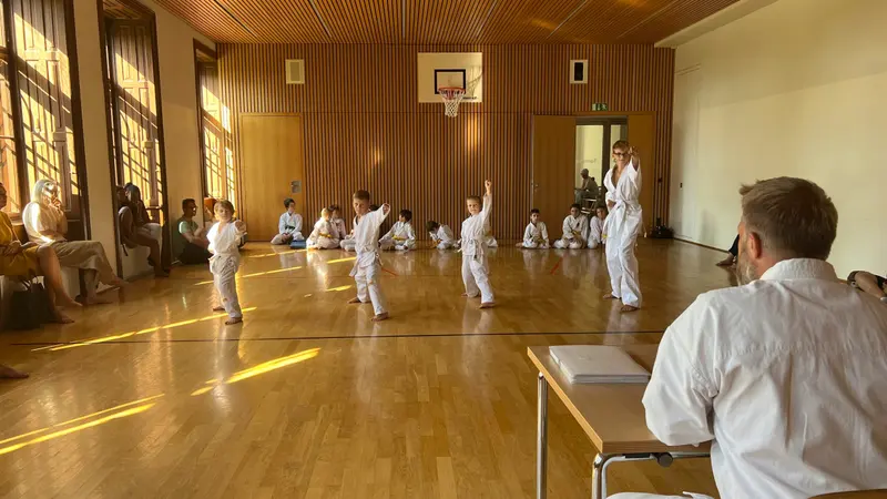 Kinder üben in der Halle, Zuschauer sitzen