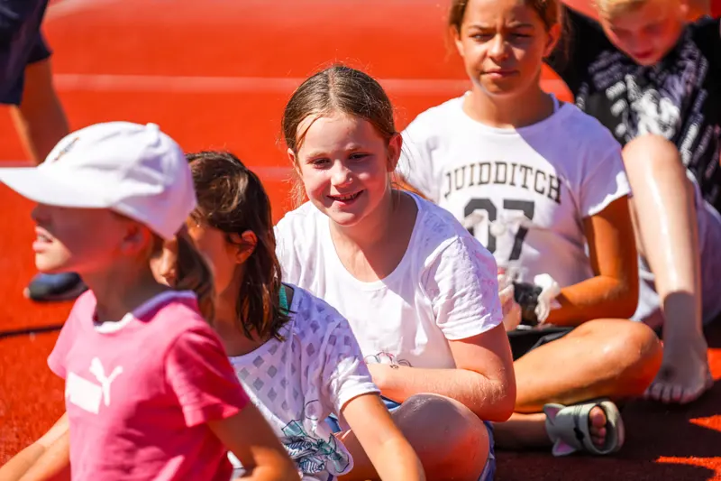 Kind in weißen Shirts sitzen lachend im Freien zusammen
