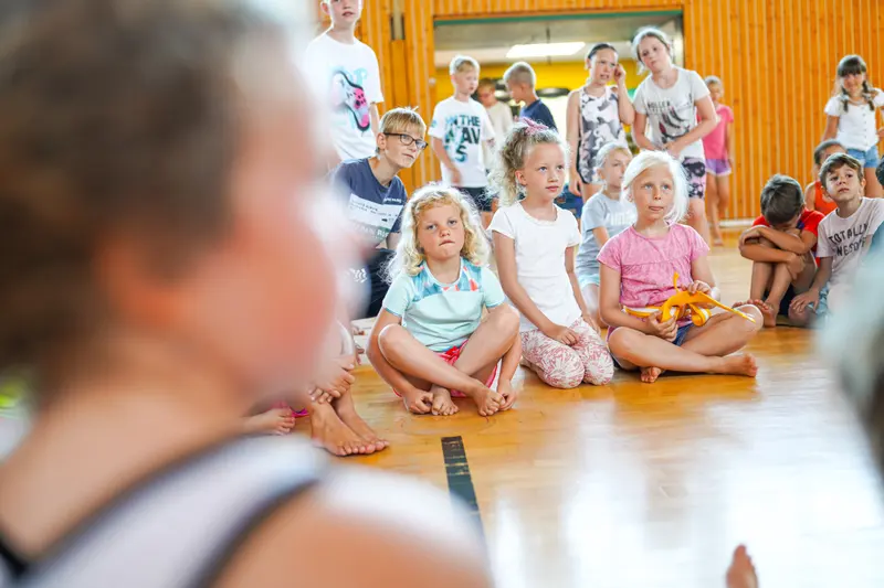 Gruppe Kinder sitzt aufmerksam auf dem Hallenboden