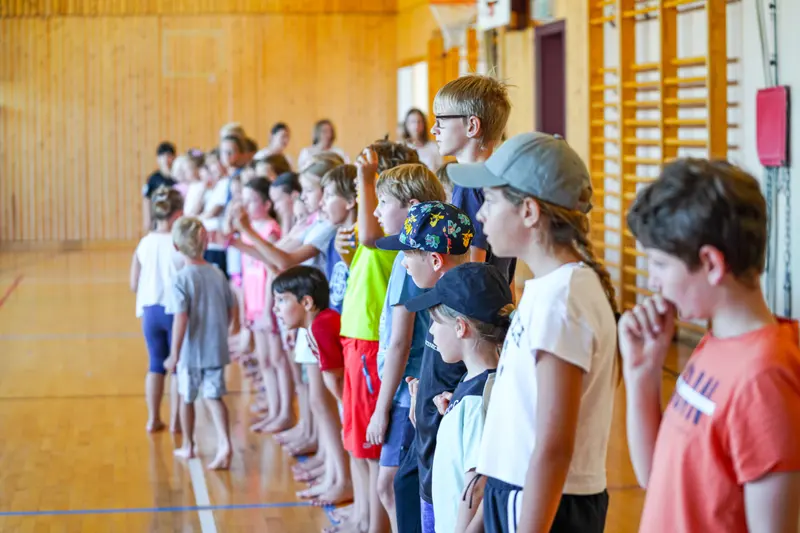 Gruppe Kinder und Jugendlicher steht in Reihe in der Turnhalle