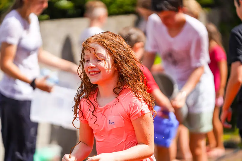 Kind mit rotem Haar, Wasser tropft im Gesicht, Wasserspiel im Freien