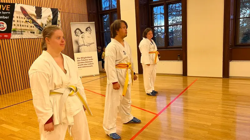 Zwei Personen im Karategi üben gemeinsam eine Technik in der Turnhalle