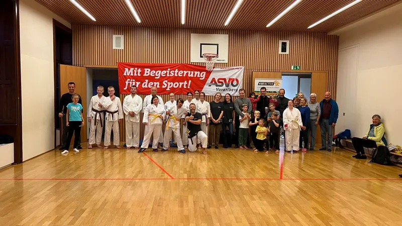 Gruppe im Karategi steht für Gruppenfoto vor ASVÖ-Banner in der Halle