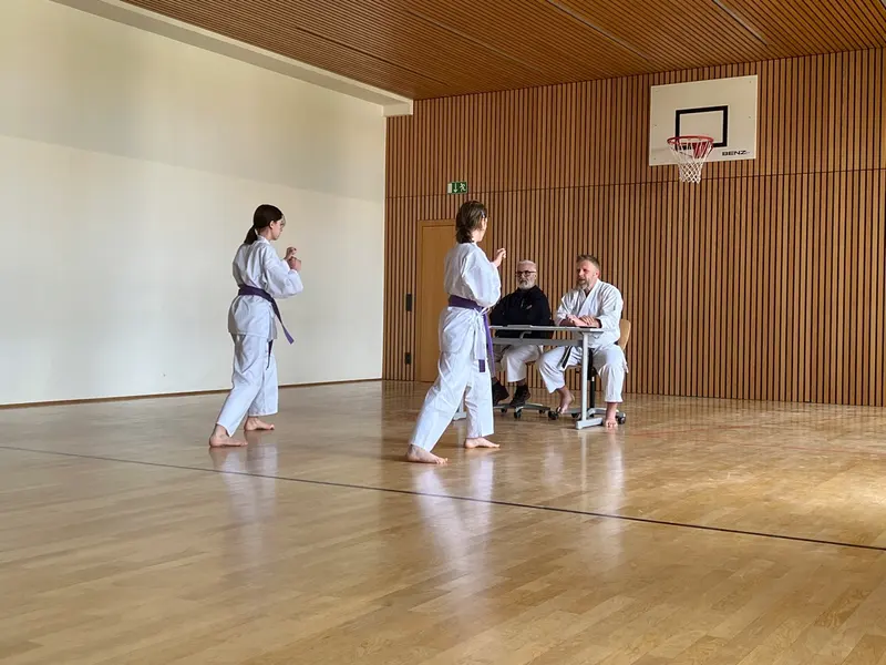 Zwei Personen gehen über den Hallenboden zu einem Tisch