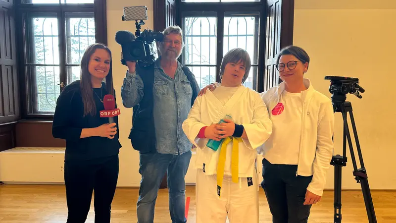 Gruppe posiert zusammen, während ein Kamerateam mit Mikrofon filmt