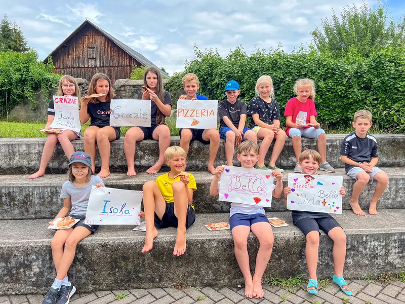 Gruppe Kinder sitzt auf Mauer und hält selbstgemachte Schilder